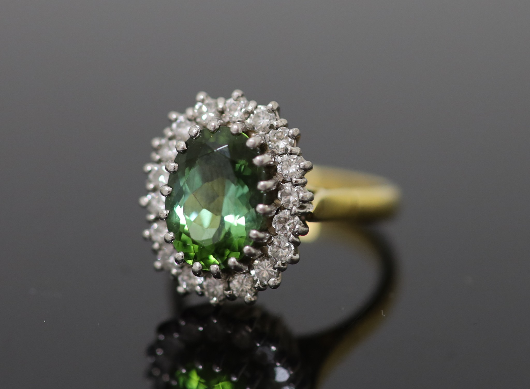 A modern 18ct gold, green tourmaline and diamond set oval cluster ring
